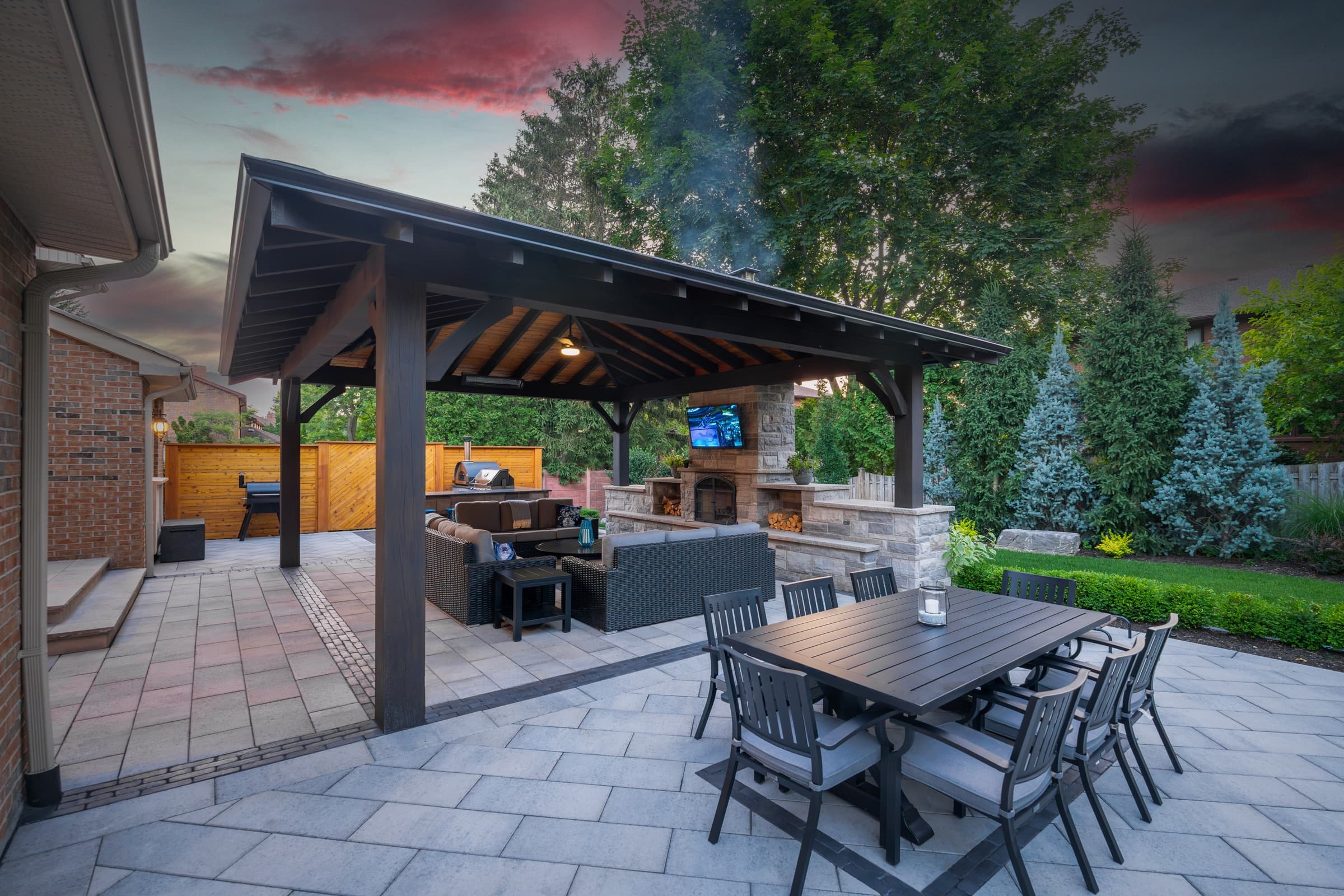 Heavy-timber pavilion sheltering an outdoor kitchen and stone fireplace